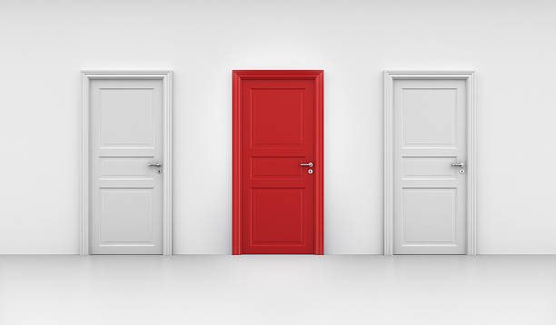 istock Three closed doors on a white wall. The center door is red 141948723