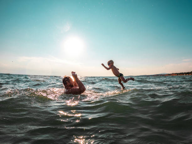 istock Cute Father And Son Jumping, Playing And Laughing In The Water While On Summer Holidays 1419487529