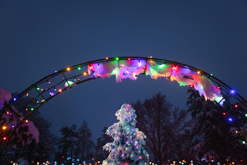 Christmas tree under colourful illuminated archway in winter.