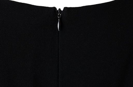 Extreme close-up of black dress with zipper on white background.