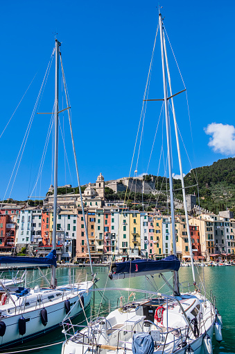 Pastel colored buildings lined up on the promenade of Porto Venere; in background, perched on the hill, are the castle and the church