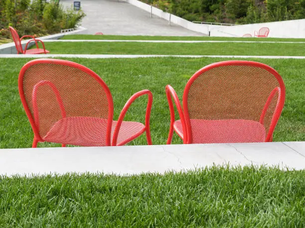 Empty bright red chairs in landscape of lawn and paths in Seattle, Washington State, USA.