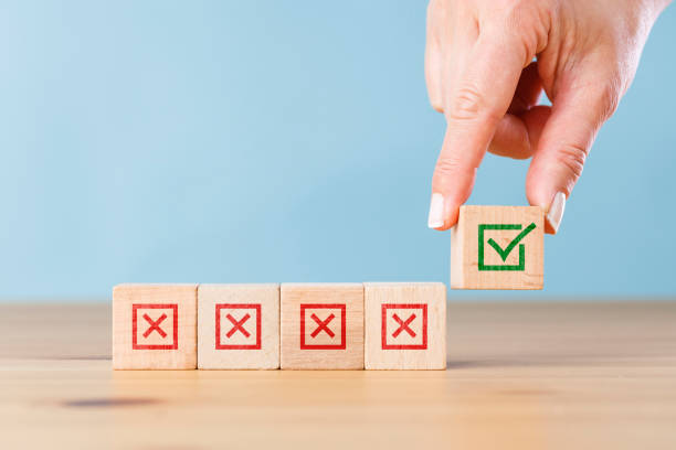 Woman hand selects checkbox with green checkmark from row of multiple boxes with red crosses. Right or Wrong. Concept of positive or negative decision making or choice of approval or rejection stock photo