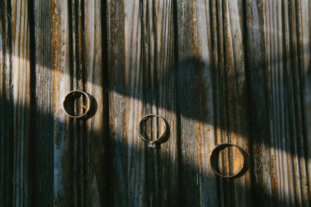 Three wedding rings on a wooden striped board Three wedding rings on a wooden striped board. allegory painting photos stock pictures, royalty-free photos & images