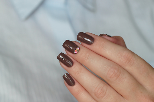dark brown chocolate nail polish with strass crystal decor and boullione close-up on fingernails