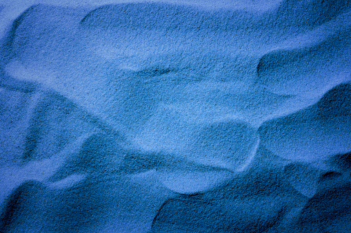 Close-up of sand wave pattern illuminated by blue moonlight.