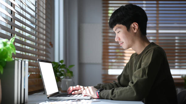 istock Focused young asian man freelancer searching information, checking email on laptop during remote working from home. 1419514186
