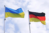 Ukrainian and German flag develops against the sky. Conflict in Ukraine