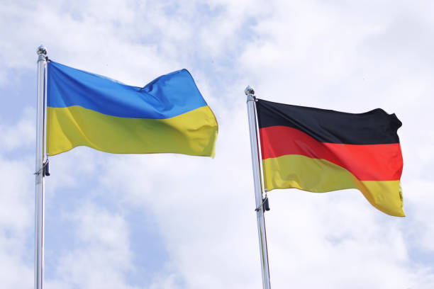 ukrainian and german flag develops against the sky. conflict in ukraine - german flag imagens e fotografias de stock