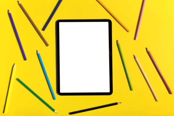 アップルペンシルと黄色の背景に白い画面を持つiPadのプロ。フラットレイ
