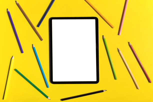 iPad pro with white screen on yellow background with Apple Pencil. flat lay
