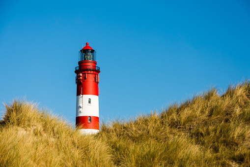 Lighthouse in the dunes of the North Frisian Island of Amrum against clear blue sky. Wittduen, North Sea, Schleswig Holstein, Germany