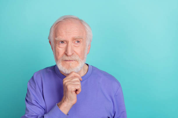 Portrait of minded clever man hand touch chin look interested empty space contemplate isolated on teal color background Portrait of minded clever man hand touch chin look interested empty space contemplate isolated on teal color background. deep pick stock pictures, royalty-free photos & images