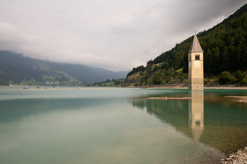 View of the artificial lake of Resia and its submerged bell tower in Curon in the province of Bolzano, Trentino Alto Adige, Italy