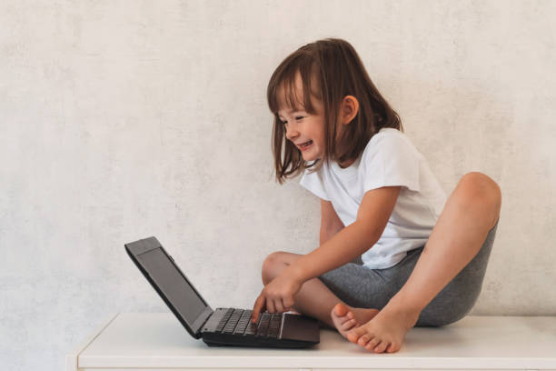 Smiling girl sitting on the closet and using a laptop