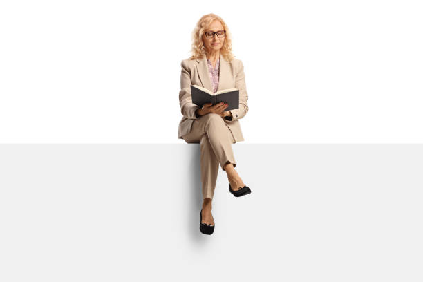 istock Female teacher sitting on a blank panel and reading a book 1419532938