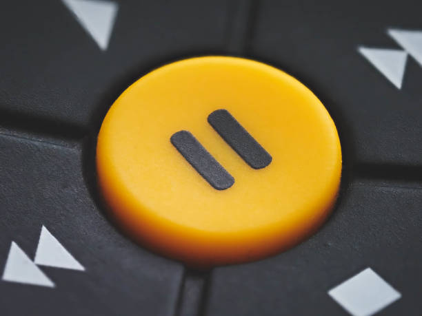 grande botão amarelo de pausa em um controle remoto de tv - pause button - fotografias e filmes do acervo