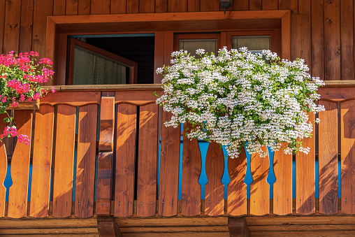 Close-up of a wooden balcony with white and red geranium flowers. Small village of Malborghetto-Valbruna in Val Canale, Udine province, Friuli-Venezia Giulia, Italy, Europe.