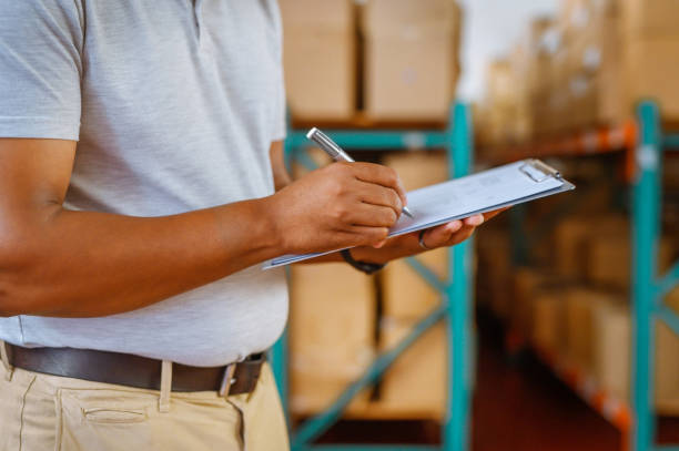 Shipping, logistics and delivery worker planning industrial supply chain manufacturing in warehouse. Wholesale manager writing paper for cargo stock, courier export and production in factory industry trabajador de envío, logística y entrega que planifica la fabricación de la cadena de suministro industrial en almacén. gerente mayorista de papel de escritura para stock de carga, exportación de mensajería y producción en la industria fabril