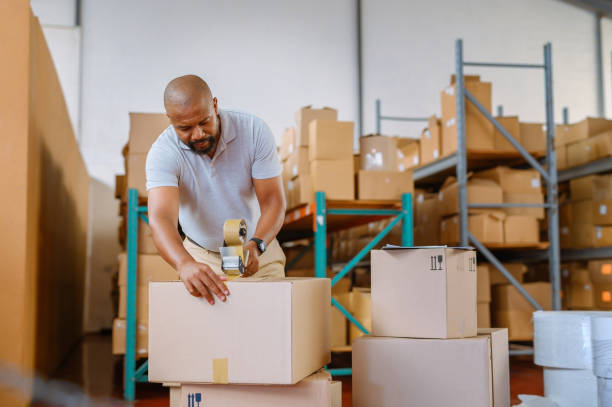 Warehouse, factory and logistics industry employee working on shipping online shopping package order at storage plant. Cargo businessman worker with cardboard box delivery, for ecommerce retail store stock photo