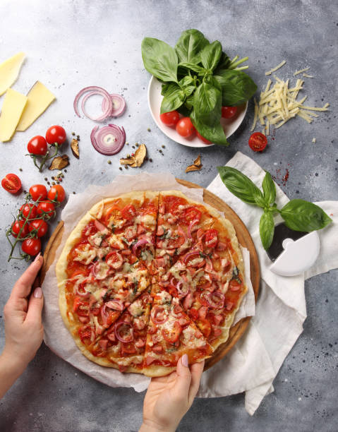 istock Italian cuisine. Pizza on a white and gray background. Cooking process. Fresh vegetables and basil. background image, copy space, pizza with hands 1419554692