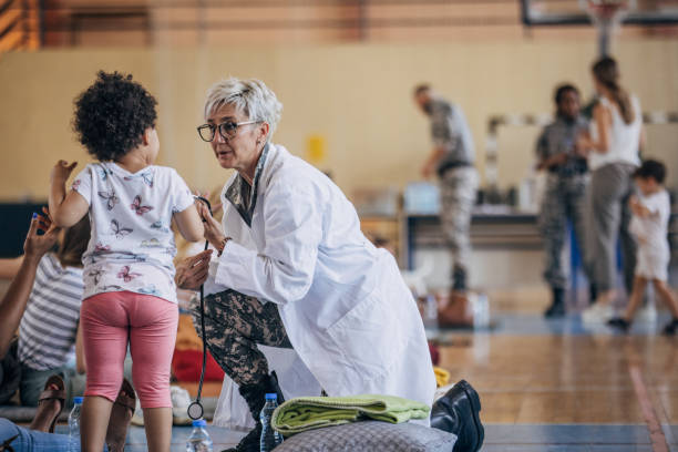 Army doctor with civilians after natural disaster Diverse group of people, soldiers on humanitarian aid to civilians in school gymnasium, after natural disaster happened in city. humanitarian aid stock pictures, royalty-free photos & images