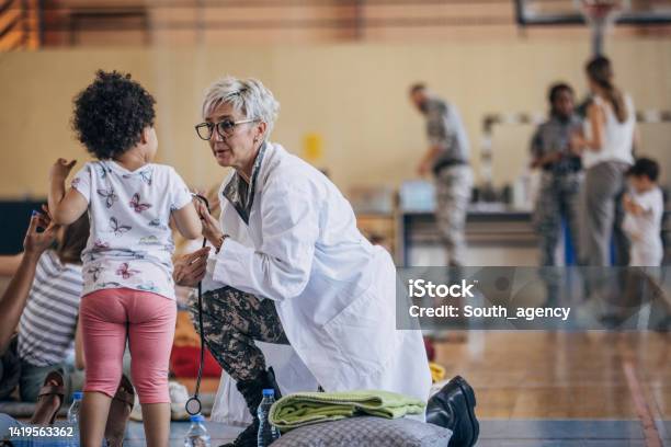 Army Doctor With Civilians After Natural Disaster Stock Photo - Download Image Now - Refugee, Assistance, A Helping Hand
