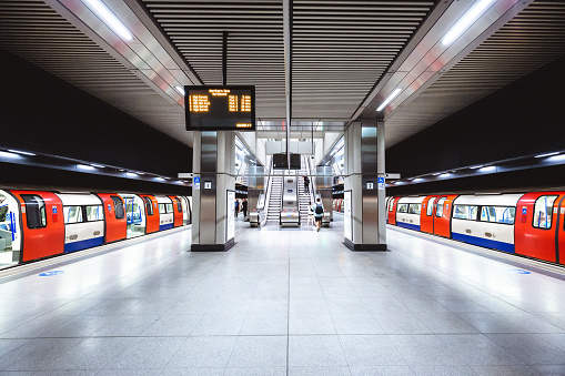 Two subway trains wait at the platform on the newly built London Underground station at Battersea Power Station. The lights of the carriage are reflected on the shiny surface of the platform.