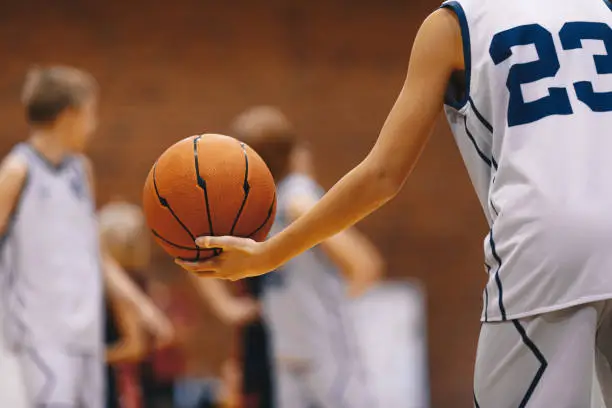 Photo of Junior level basketball player holding game ball at practice drill. Basketball training session for kids