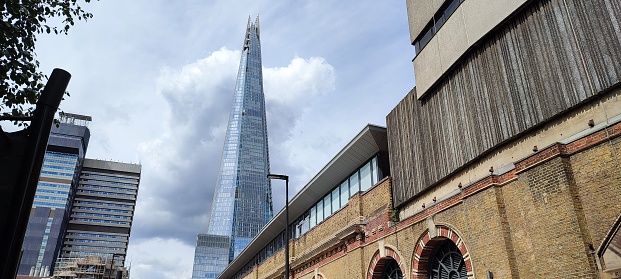 Southwark, London - The Shard and railway arches viewed from St Thomas Street behind London Bridge station. People are walking along the street, and signs denoting a 20 miles per hour speed limit can be seen