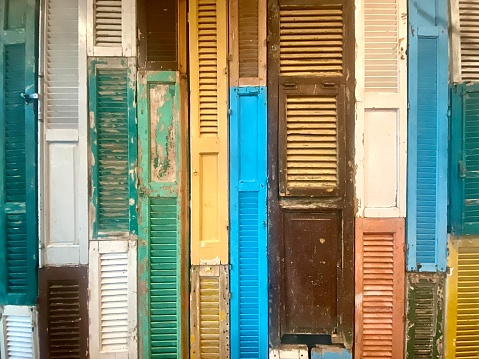 Horizontal close up of community public wall covered in rustic painted wood shutter door frames compiled to create feature wall in Mullumbimby Australia
