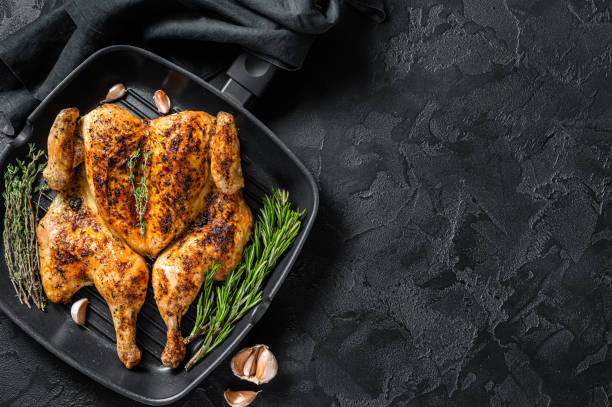 istock BBQ spatchcocked barbecue whole chicken on grill pan. Black background. Top view. Copy space 1419567229