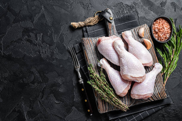 istock Fresh Raw chicken drumsticks legs on wooden cutting board. Black background. Top view. Copy space 1419568132