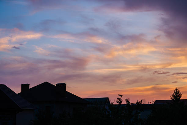 Sunset sky over buildings, pink orange blue colors.