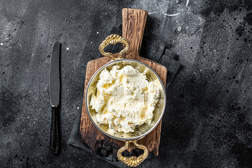 Kaymak Clotted cream, butter cream in a rustic pan. Black background. Top view.