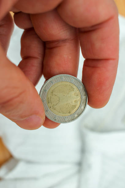 istock a two euro coin from Germany between my fingers 1419570303