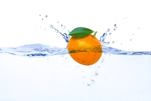 Tangerine or clementine orange fruit with green leaf falling in water splash isolated on white background.