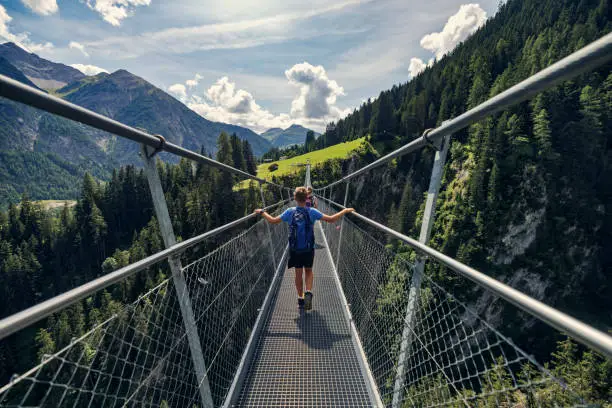 Photo of Mother and teenage son walking on suspended bridge in the Austrian mountains - Alps, Tyrol, Austria.