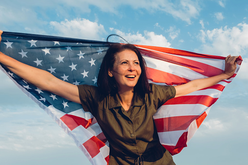 Happy middle aged woman holding american flag.