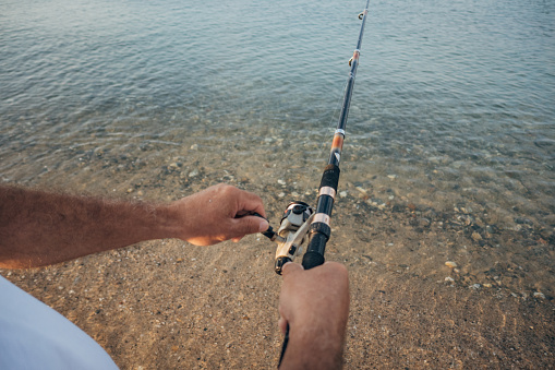 A fisherman's hands hold a fishing rod