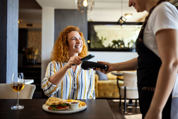 Smiling young making contactless payment with smart phone
