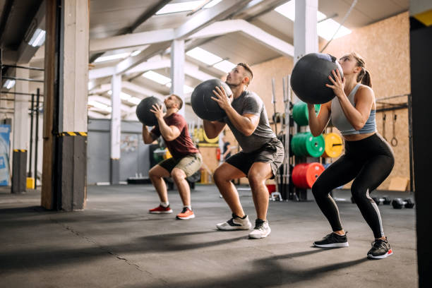 Fitness class using heavy weight balls Group of athlete people exercising with weighted balls at cross training gym exercise class stock pictures, royalty-free photos & images