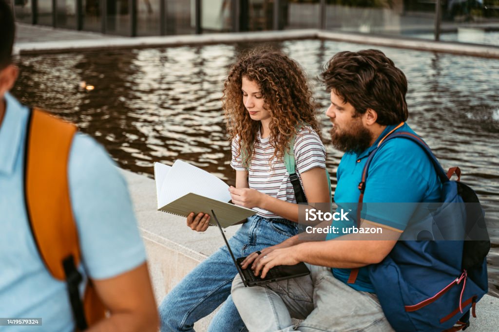 Two Students Comparing Notes Two Students Discussing Their Class Notes On The University Campus ...
