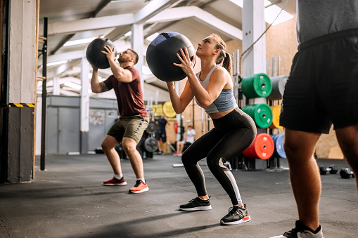 Group of athlete people exercising with weighted balls at cross training gym