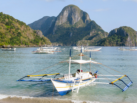 Scenic view of boats moored in sea with mountains in background, Coron Island, Coron, Philippines.