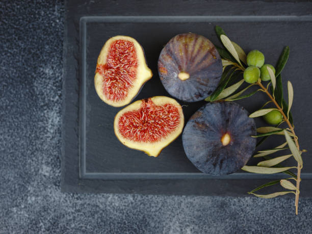fresh ripe figs fruit and olive branch on dark table stock photo