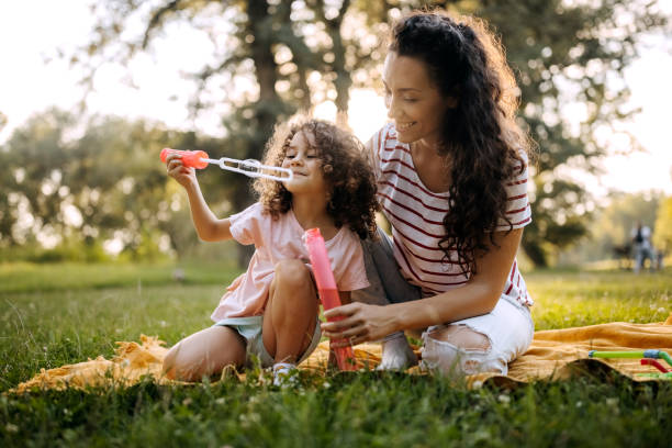 istock Mother and daughter having fun in park with soap bubbles 1419583740