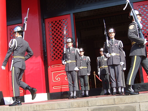 Taipei.Taiwan – Octorber 21, 2007:This is the Changing of the Guard of National Revolutionary Martyrs' Shrine in Taiwan.\nThe changing of the guard ceremony takes place in the central square. \nTwo guards stand at the main gate and main hall of Martyrs' Shrine.\nSoldiers that have been selected from the Army, Navy, Air Force will change once an hour.\nSoldiers who have passed strict conditions and undergone training do not move and do not change their facial expressions like dolls.\nThe guards form a line of 5 people. Uniforms differ from army to army.Eligible to become a soldier are High school graduate or higher, no criminal record, height 175㎝ ~ 195㎝, weight 65kg ± 1kg.
