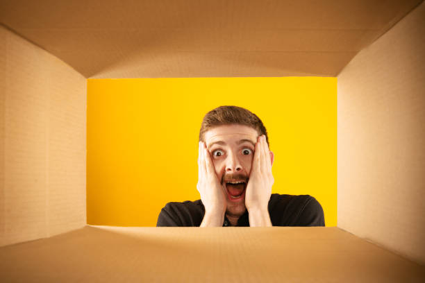 istock Incredible. Surprised man unpacking, opening carton box and looking inside with wide open eyes. Delivery, surprise, gift, wow emotions concept. 1419588853