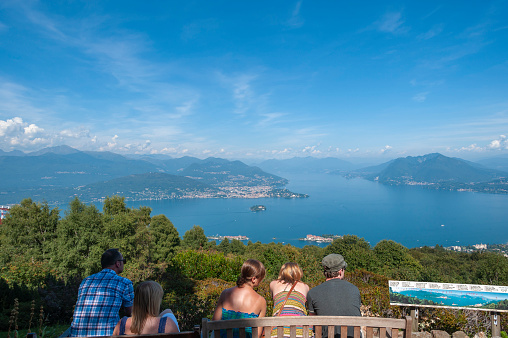 Stresa, Italy - August 17, 2018: Tourists in the Giardino Botanico Alpinia park overlooking Lake Maggiore and the Borromean Islands near Stresa. Stresa is a town in Piedmont in northern Italy